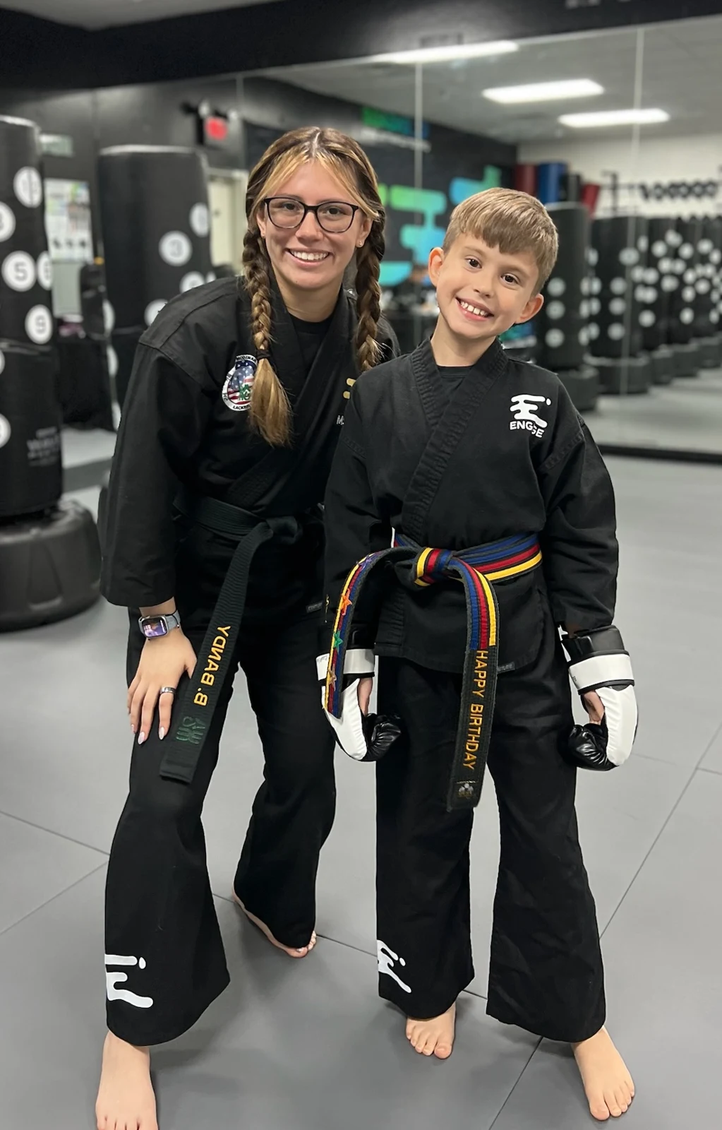 Birthday child wearing a birthday belt beside a coach at Engage Lifestyle Martial Arts in Henderson