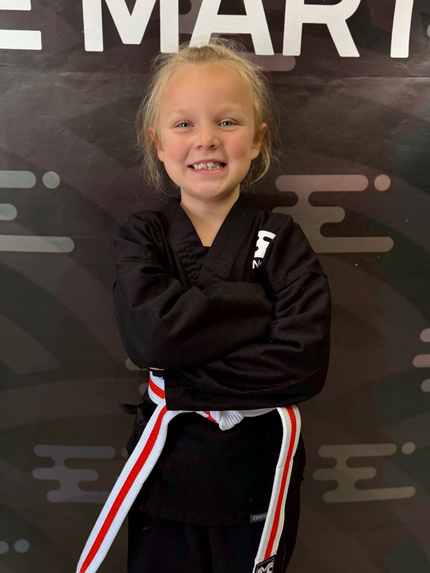 Smiling young Engage student in black uniform with white belt